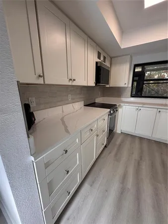 a kitchen with granite countertop white cabinets and white appliances