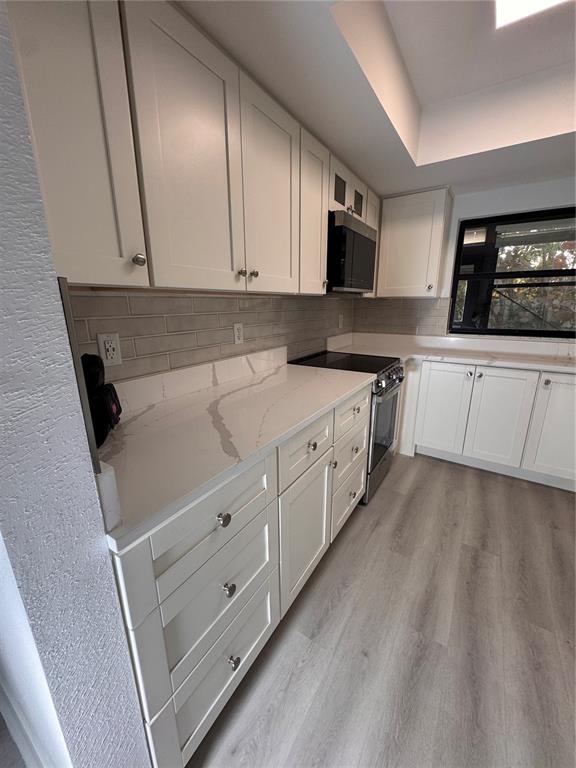 1 Windrush Boulevard, Unit 103 Indian Rocks Beach, FL 33785 - Photo 3 of 16 a kitchen with granite countertop white cabinets and white appliances