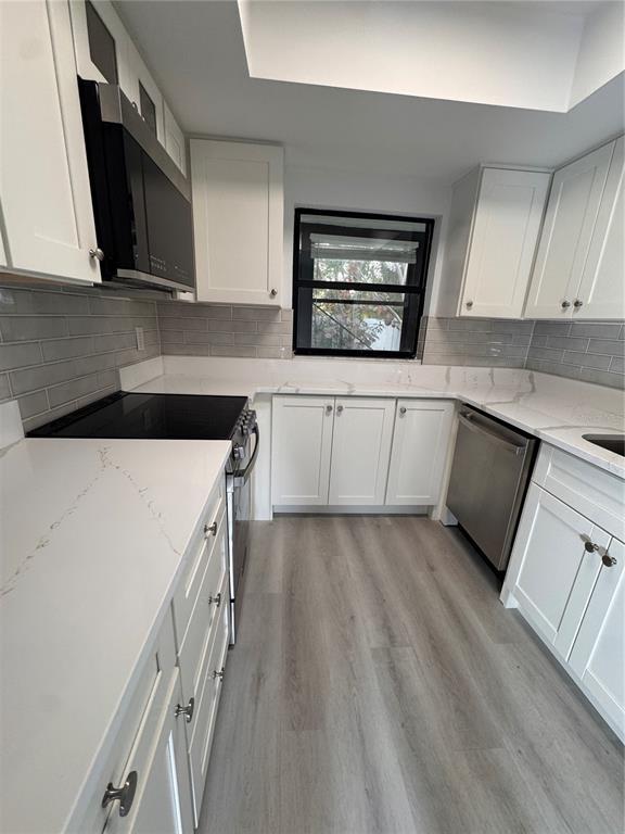 1 Windrush Boulevard, Unit 103 Indian Rocks Beach, FL 33785 - Photo 5 of 16 a kitchen with a sink a microwave and cabinets