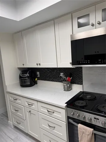 a kitchen with white cabinets and appliances