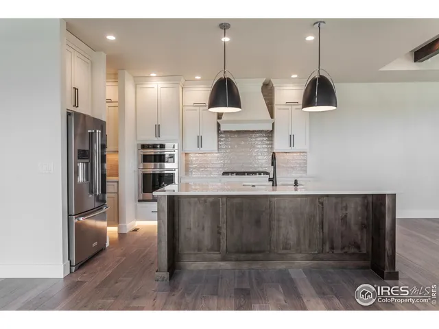 a kitchen with kitchen island a counter top space a sink stainless steel appliances and cabinets