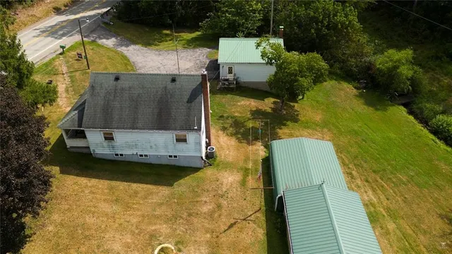 an aerial view of a house with a yard and trees all around