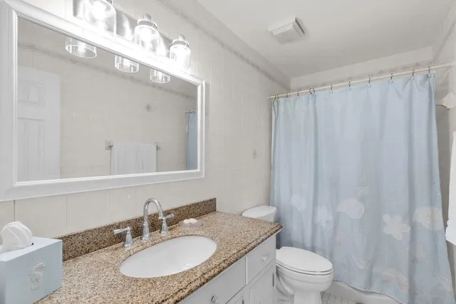 a bathroom with a granite countertop sink vanity mirror and toilet