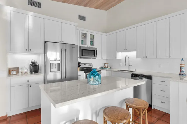 a kitchen with a refrigerator a stove a sink and chairs