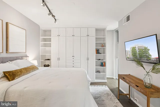 a bedroom with a bed and a flat tv screen on the dresser