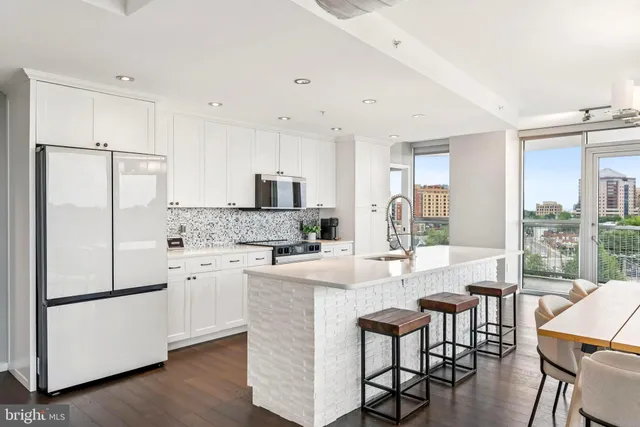 a kitchen with stainless steel appliances granite countertop a refrigerator a stove a sink a dining table and chairs