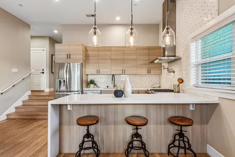 a kitchen with stainless steel appliances kitchen island a table chairs in it and wooden floors