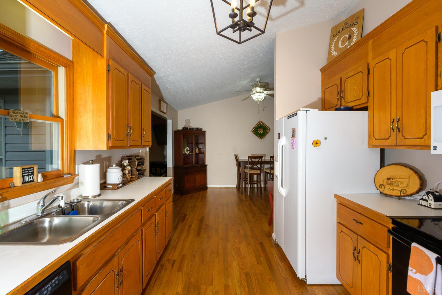 151 Wilderness Road Rustburg, VA 24588 - Photo 24 of 63 a kitchen with stainless steel appliances granite countertop a refrigerator a stove and a sink with wooden floor