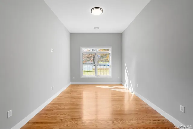 a view of an empty room with window and wooden floor
