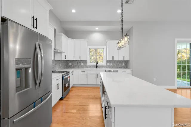 a large kitchen with kitchen island white cabinets and stainless steel appliances