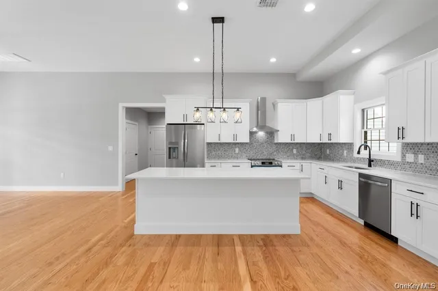 a large kitchen with granite countertop a stove top oven a sink dishwasher and white cabinets with wooden floor