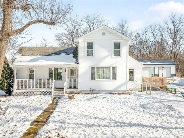 a front view of a house with a yard covered in snow