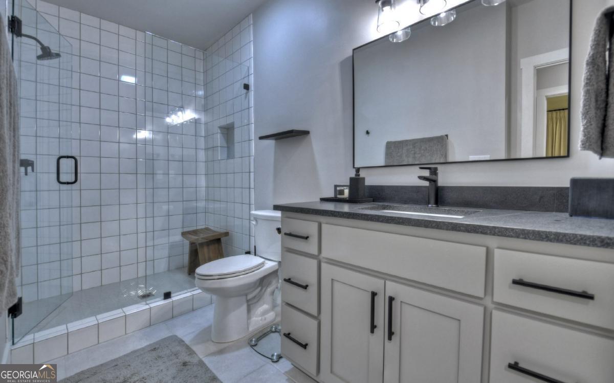 375 Blue Berry Ridge, Unit 2B Morganton, GA 30560 - Photo 25 of 61 a bathroom with a granite countertop toilet a sink and a shower