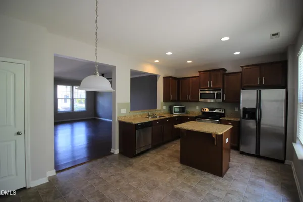 a kitchen with refrigerator a oven a sink a counter top space and cabinets