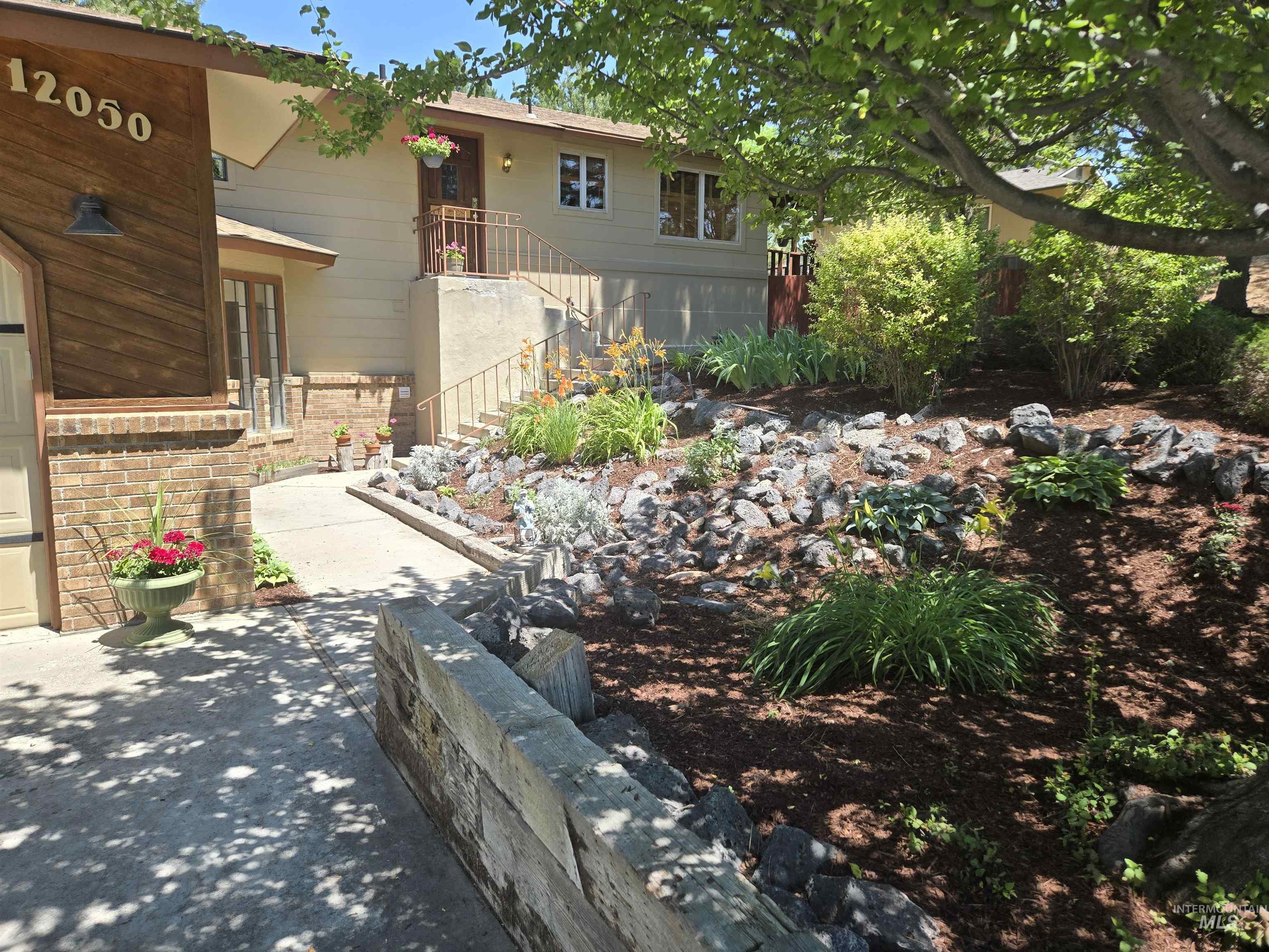 12050 West Hidden Valley Rim Road Boise, ID 83709 - Photo 2 of 39 Landscaped front yard with a rock garden and mature plantings