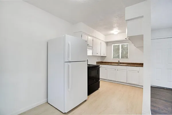 a kitchen with a refrigerator a stove top oven and cabinets