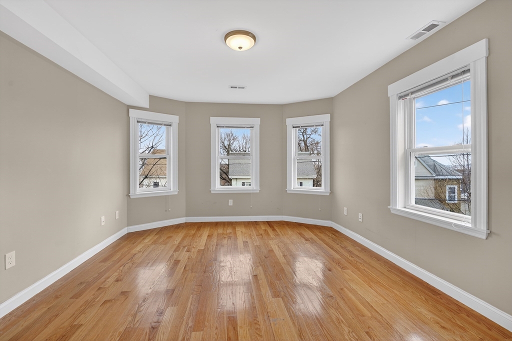 a view of empty room with wooden floor and fan
