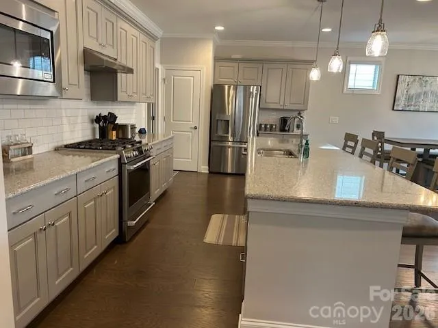 a kitchen with stainless steel appliances granite countertop a sink a stove and a refrigerator