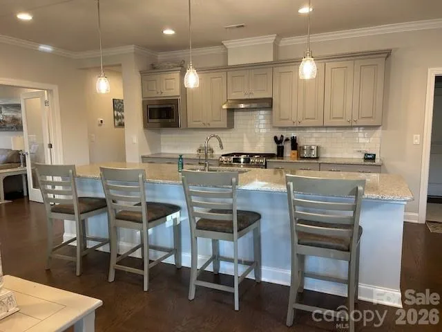 a living room with stainless steel appliances kitchen island granite countertop furniture wooden floor and a kitchen view