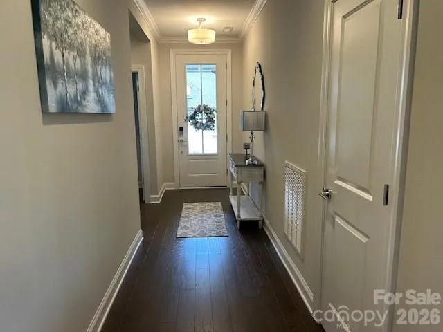 a view of a hallway with wooden floor and a bathroom