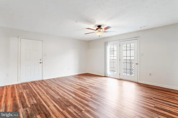 a view of an empty room with a window and wooden floor