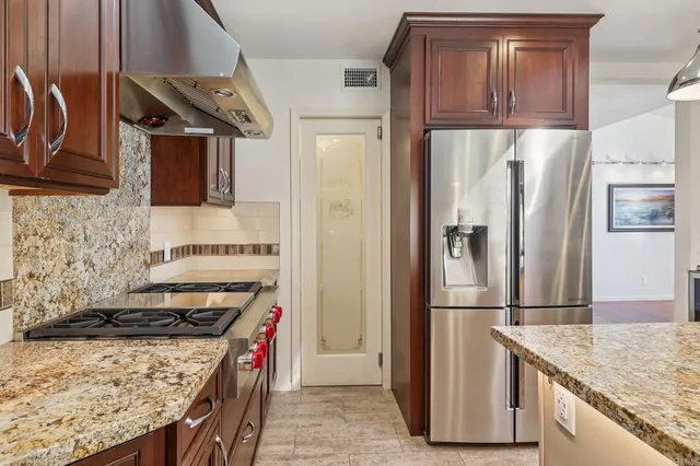 a kitchen with stainless steel appliances granite countertop a refrigerator a stove and a sink with wooden floor