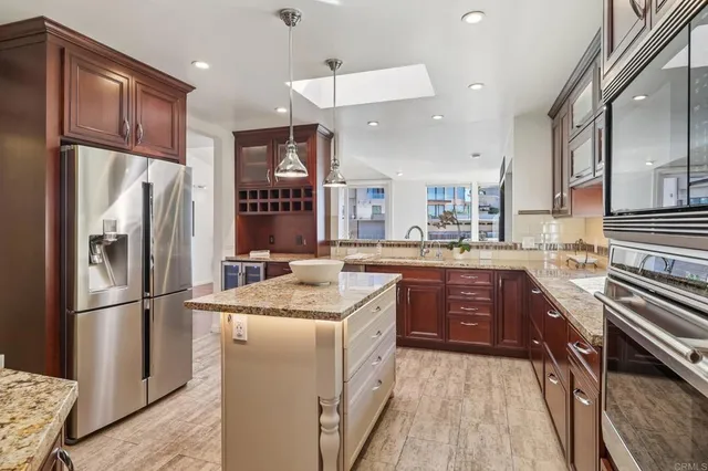 a kitchen with stainless steel appliances granite countertop a refrigerator a sink dishwasher a stove and white cabinets with wooden floor