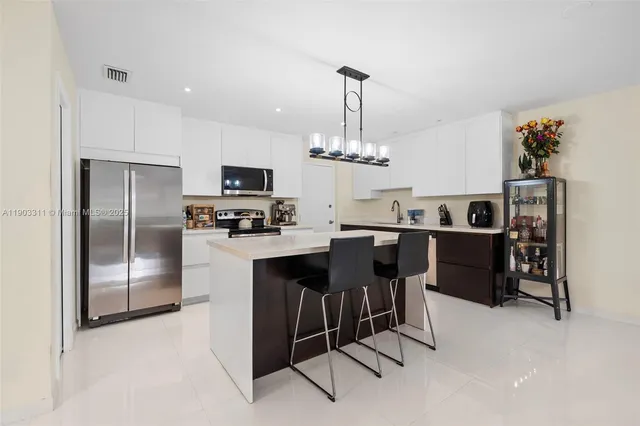 a kitchen with kitchen island granite countertop stainless steel appliances a sink and a refrigerator