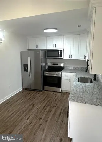 a kitchen with granite countertop a refrigerator and a sink