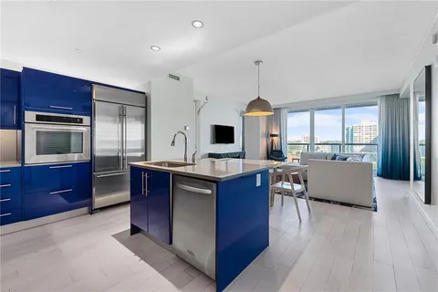 a kitchen with stainless steel appliances granite countertop a stove a sink dishwasher a refrigerator and a dining table with wooden floor