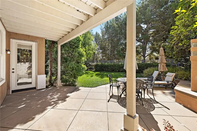 a backyard of a house with table and chairs plants and large tree