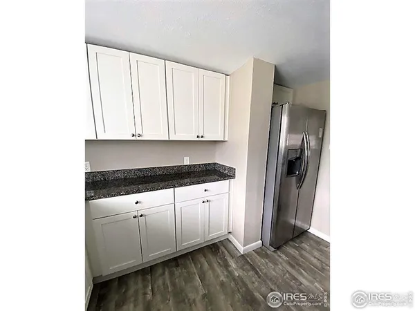 a kitchen with granite countertop white cabinets and refrigerator