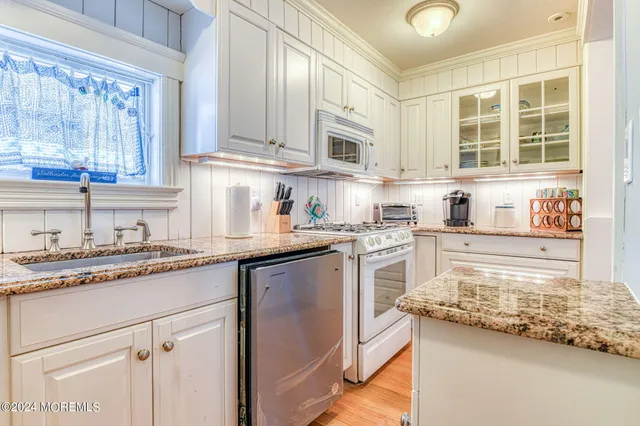 a kitchen with granite countertop stainless steel appliances a sink window and cabinets