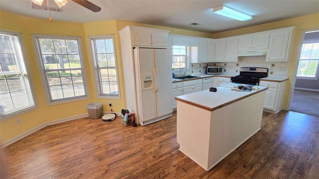 352 Olde Wick Trail Hoschton, GA 30548 - Photo 11 of 34 a kitchen with stainless steel appliances a stove a sink a refrigerator white cabinets and wooden floor