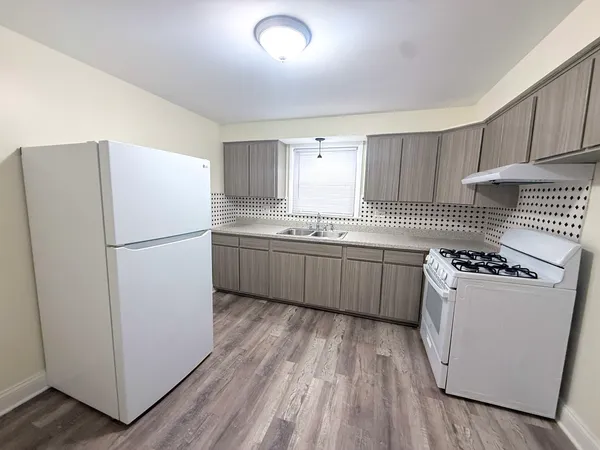 a kitchen with a sink a stove cabinets and wooden floor
