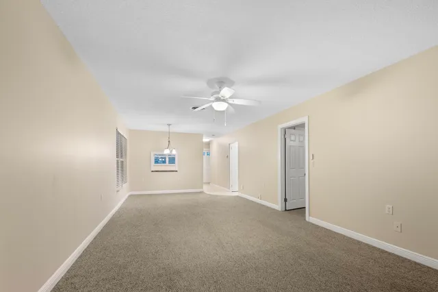 an empty room with ceiling fan and window