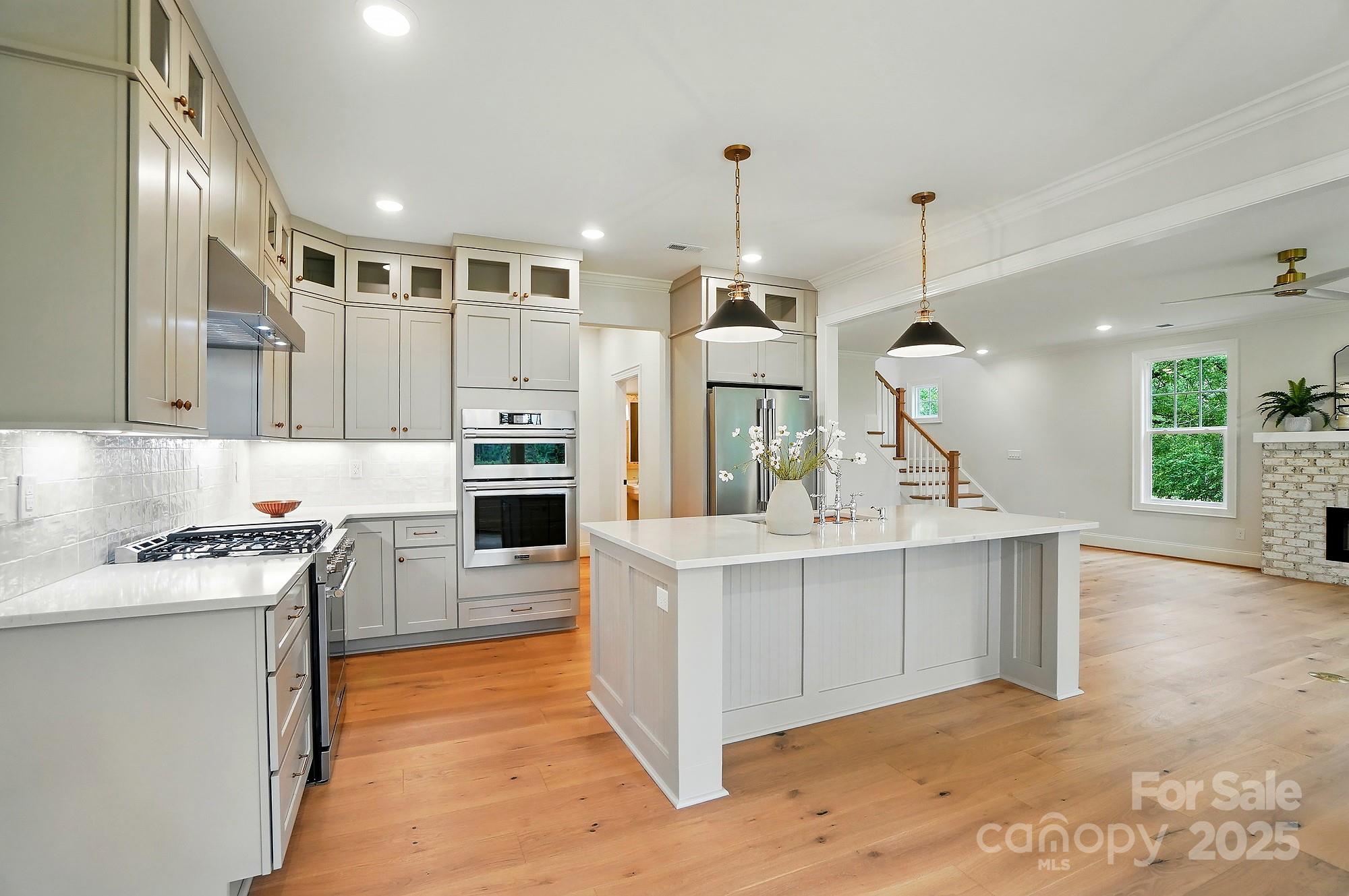 9315 Simpson Road Waxhaw, NC 28173 - Photo 15 of 45 a large kitchen with stainless steel appliances kitchen island granite countertop a stove a sink a refrigerator and white cabinets with wooden floor