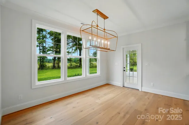 a view of an empty room with wooden floor fridge and a window