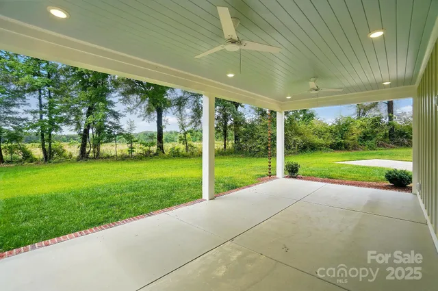 a view of a house with a big yard potted plants and large tree