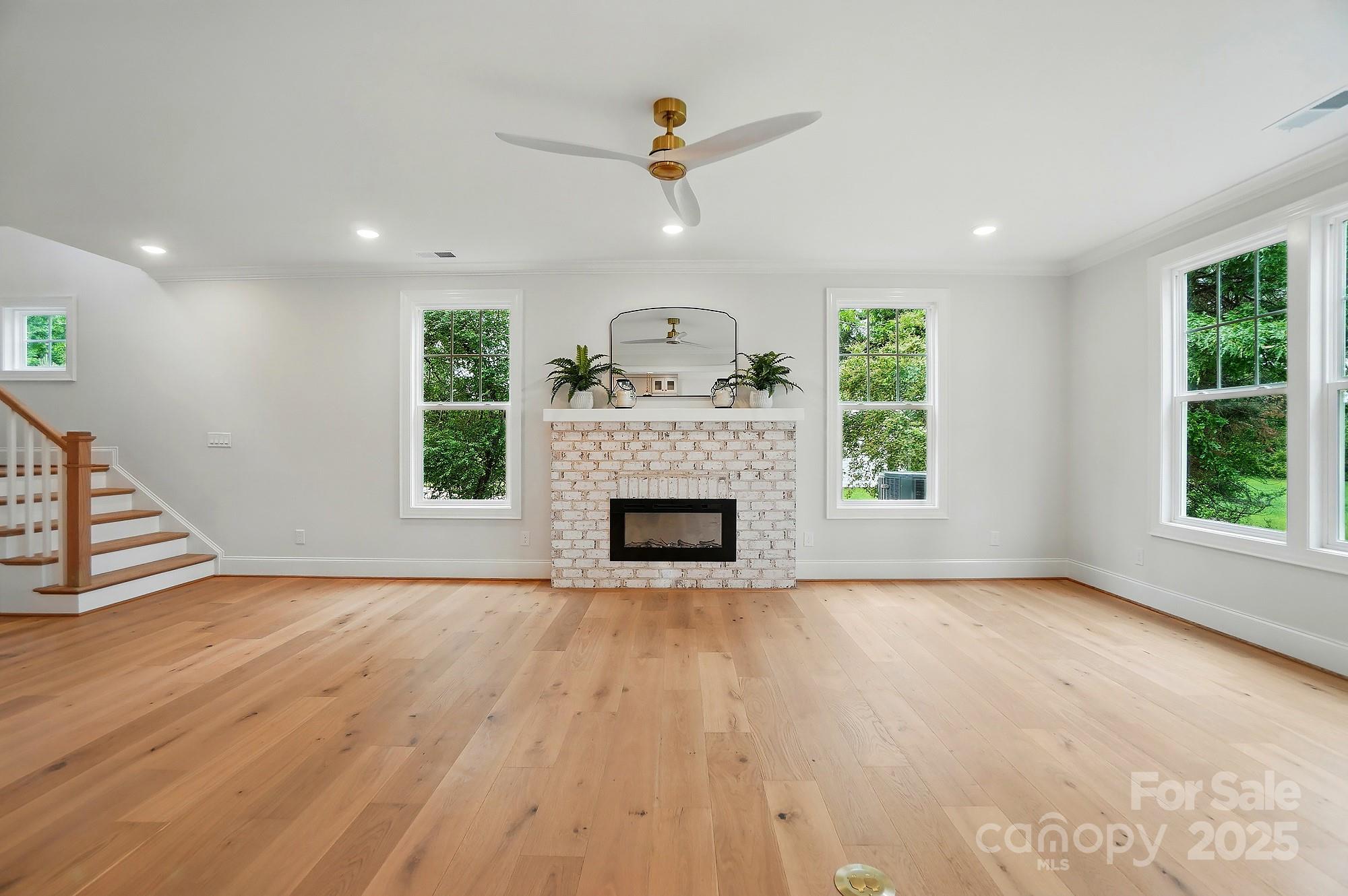 9315 Simpson Road Waxhaw, NC 28173 - Photo 8 of 45 a view of a livingroom with a fireplace a ceiling fan and windows
