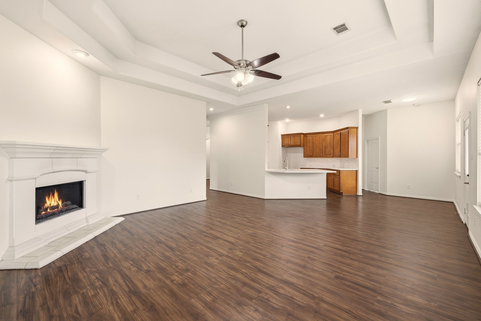 25207 Oak Star Drive Spring, TX 77389 - Photo 8 of 18 a view of a kitchen with a ceiling fan wooden floor and a fireplace