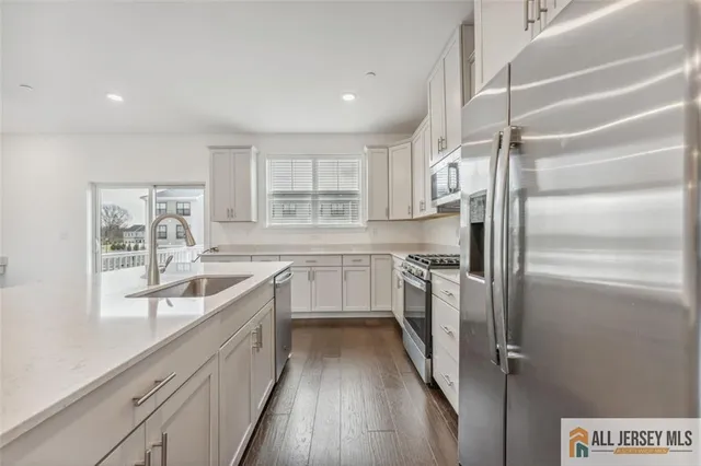a kitchen with a refrigerator a sink and dishwasher with wooden floor