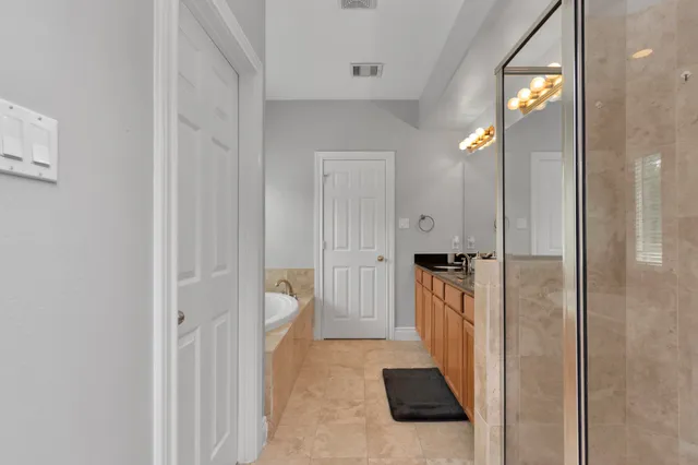 a view of a hallway with wooden floor and a bathroom