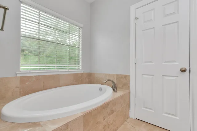 a white bath tub sitting in a bathroom next to a window