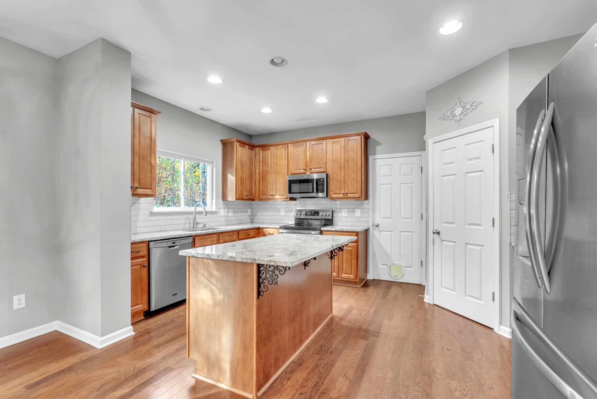 3924 Signature Court Smyrna, TN 37167 - Photo 5 of 35 a kitchen with stainless steel appliances granite countertop a refrigerator a sink dishwasher a stove and a dining table with wooden floor