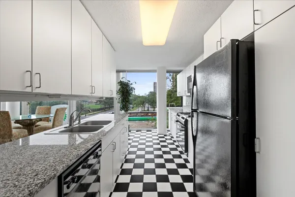 a kitchen with granite countertop a refrigerator a sink a stove a washer and dryer