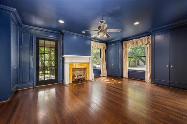 an empty room with wooden floor fireplace and windows