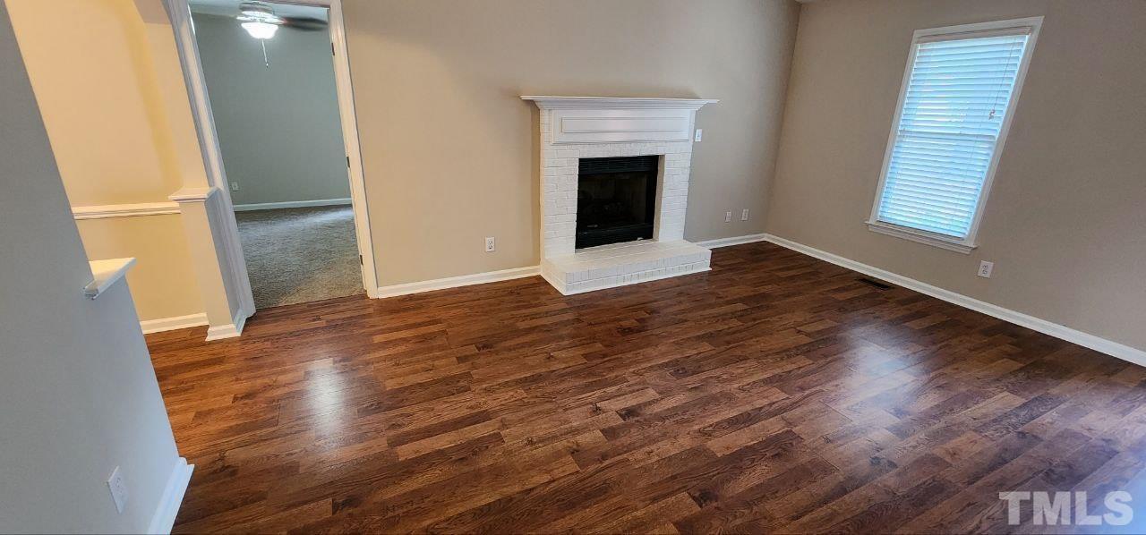 745 Brewer Circle Wake Forest, NC 27587 - Photo 10 of 18 an empty room with wooden floor and fireplace