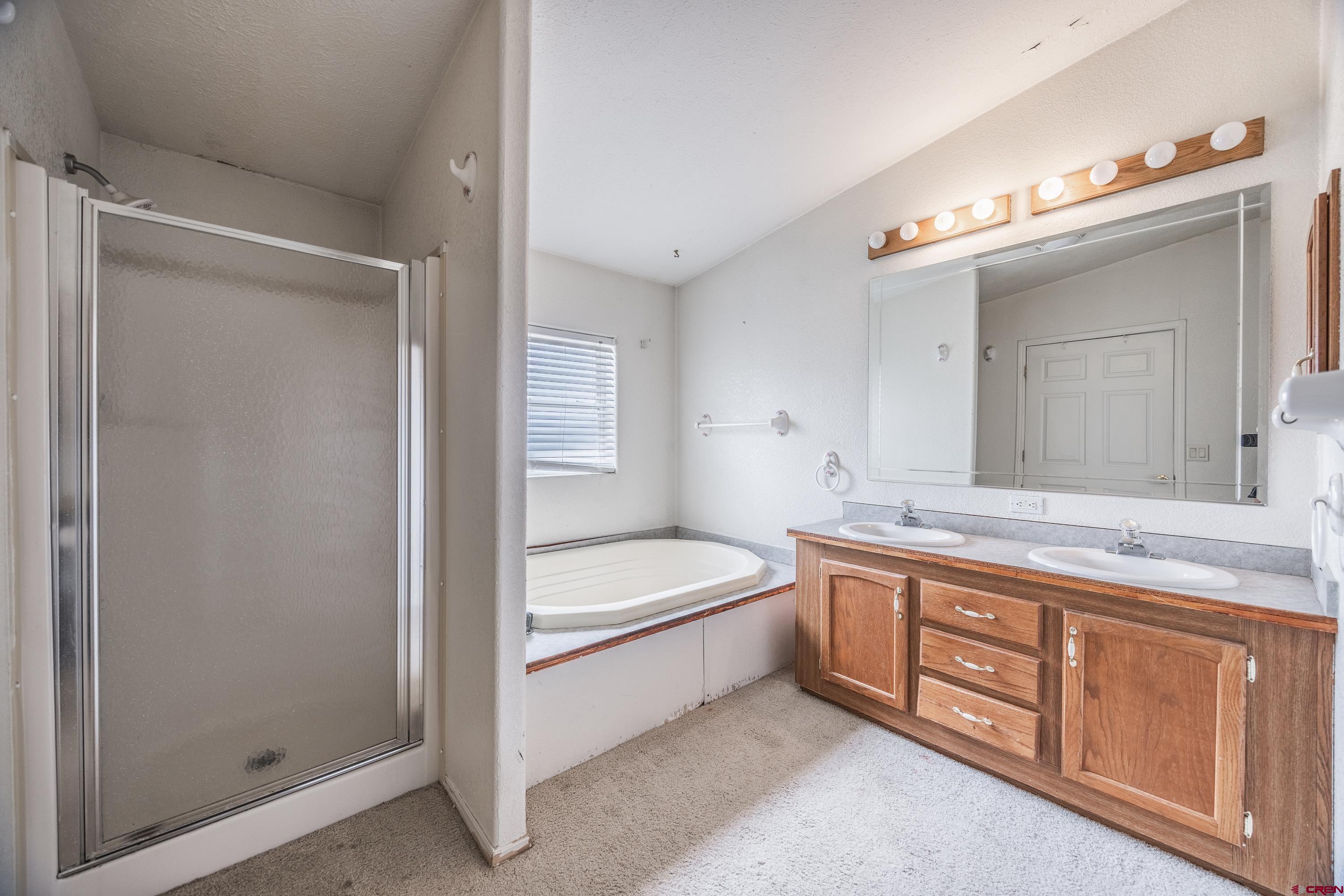 17377 Breeze Road Delta, CO 81416 - Photo 24 of 45 a spacious bathroom with a double vanity sink a mirror and a bathtub