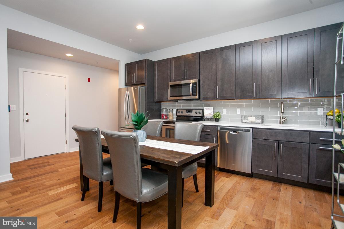 5938 Henry Avenue, Unit 21 Philadelphia, PA 19128 - Photo 4 of 19 a kitchen with a table chairs refrigerator and cabinets